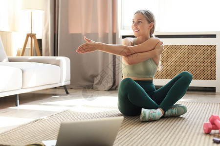 健身美丽苗条的女人在家里的客厅里做健身伸展运动 留在家里活动 运动 健康的生活方式运动员房间房子健身房女孩地面互联网重量女士有氧有氧运动高清图片素材