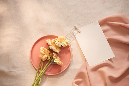 粉色邀请函信封盘子里的鲜花和黄色背景的布料和纸张粉色婚礼织物信封正方形邀请函花朵问候语空白艺术背景