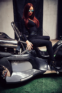 摩托三轮车时尚的年轻女人 假扮坐在新的三角架上化妆品店铺车辆购买者黑发三轮车兴趣节日头发发动机背景