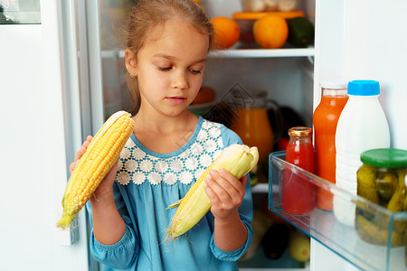 小女孩站在冰箱前 选择食物 坐在冰箱前面蔬菜女士童年水果饮食饥饿孩子小吃午餐营养背景图片