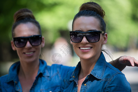 有太阳眼镜的姐妹姊妹成人女孩们幸福头发双胞胎公园朋友们衣柜女士微笑可爱的高清图片素材