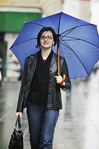 妇女带着雨伞在街上流浪购物季节下雨蓝色城市天气夹克雨量街道风暴背景图片