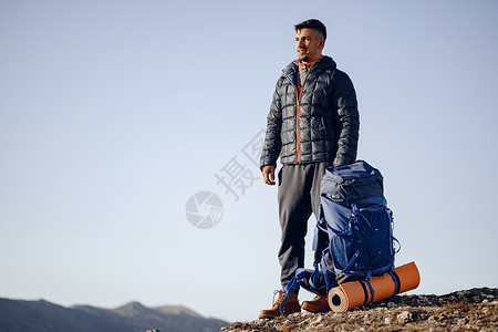 在山顶站立的徒步旅行设备中的男性背包男活动自由高度耐力男人顶峰天空爬坡农村旅游背景图片