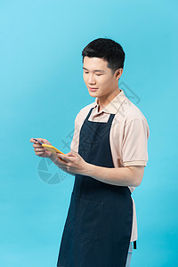 年轻厨师使用智能手机及信用卡进行在线银行业务的照片 (请访问InfoFinland上的官方网站)背景图片