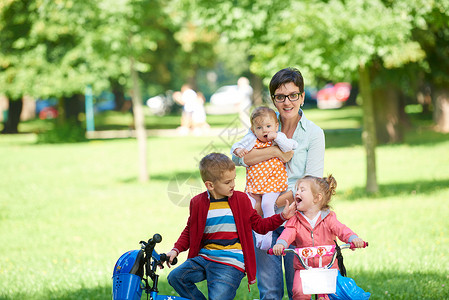 公园中快乐的年轻家庭女儿婴儿女士自行车乐趣幸福闲暇男生儿子女孩童年高清图片素材