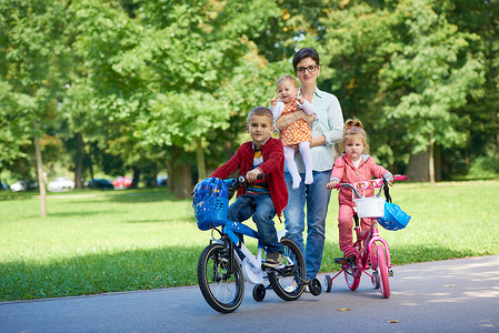 公园中快乐的年轻家庭孩子女士幸福婴儿父母闲暇自行车童年旅行男生乐趣高清图片素材