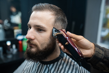 理发店主用剪发机给男人理发修剪沙龙理发师客户胡子美容师梳子发型师剃刀程式化店铺高清图片素材