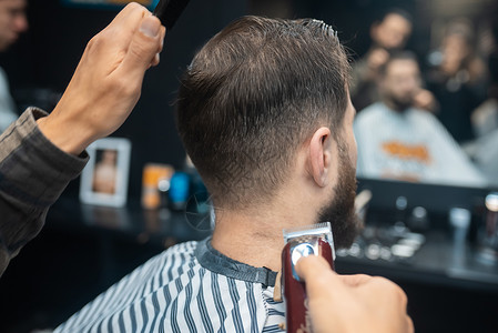 理发店主用剪发机给男人理发男性客户职业胡须沙龙治疗造型师剪子商业程式化发型设计高清图片素材