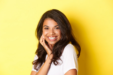 轻浮的美丽的非洲裔美国女性的形象 微笑的轻浮和感人的脸 广告美容产品 站在黄色背景下发型促销多样性情感员工黑发女孩成人女士工作背景