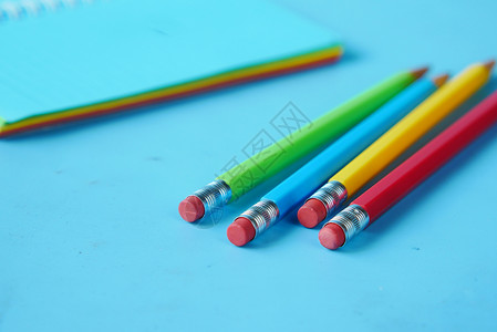 特写笔记本上的彩色铅笔黄色蜡笔孩子红色蓝色绿色背景图片