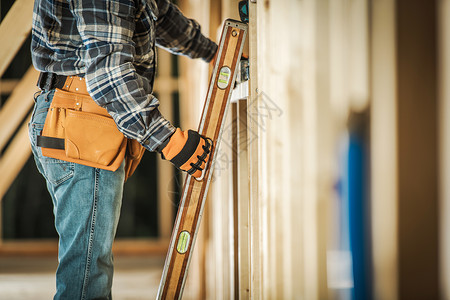 承包商工人使用水平仪工具确保木框对齐正确 施工工具和建筑技术背景图片