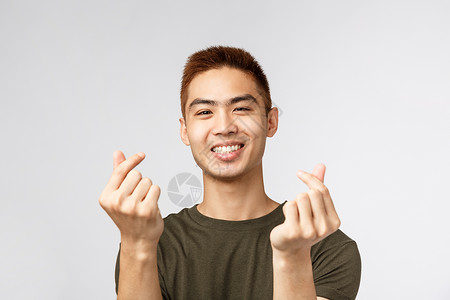 人 不同的表达方式和生活方式的概念 可爱的亚洲男人 发型时尚 展示韩国指心 微笑可爱 表达同情或喜欢 站在灰色背景商业情绪互联网男性高清图片素材