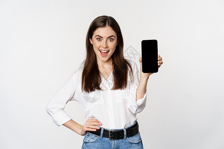 首页界面女装快乐的笑笑女人展示智能手机应用程序界面 移动电话屏幕 宣传出价演示 站在白背景上站立 她们欢欣喜地微笑着女性技术工人网络顾问管理背景