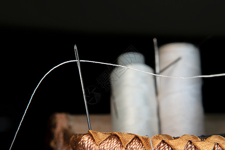 线穿过缝纫针的眼睛 缝纫和针线活课程 手工和手工制作车间 纺织业的工作场所 绣花针卡在线轴卷轴材料纺织品裁缝女裁缝别针缝纫机职场背景图片