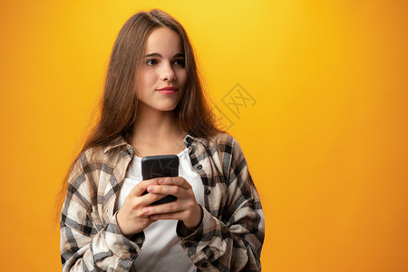 使用智能手机微笑的年轻女孩的肖像女士视频青少年休闲装享受女性装置阅读细胞技术背景图片
