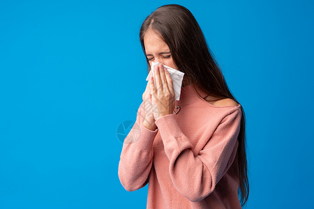 女孩在蓝背景下打鼻涕疾病盒子女性白色组织鼻子流感喷嚏过敏青少年病毒高清图片素材