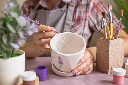 手画的花穿灰色围裙的妇女给白花瓷锅漆女性女孩作坊工匠创造力黏土活动静物工具身体背景