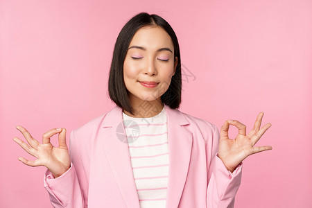 保持冷静 微笑的亚洲年轻女性冥想 练习瑜伽 工作中的正念和放松 呼吸 面容愉悦地吸入空气 站在粉红色背景上人士学生标识广告购物大背景图片