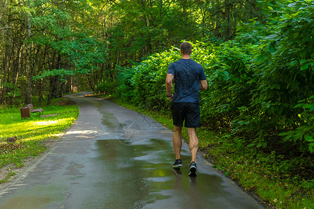 一名男子运动员在户外的公园里跑步 在森林周围 橡树绿草年轻持久的运动员跑步健身户外适合腿男性 外面的树木 夏季身体脚部伸展背景图片