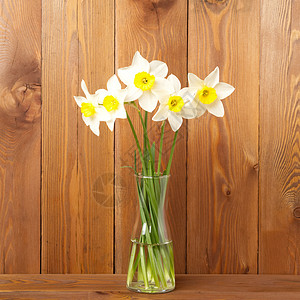 一束鲜花 木桌中间花瓶里的水仙花 对面是棕色木墙 文本的空白空间背景图片