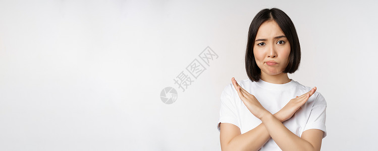 身穿短衫站在白背景上站立的亚洲韩国妇女肖像 禁止手势 举臂十字牌 穿着短袖圆领汗衫技术广告企业家互联网成人情感女士工作室商业情绪背景图片