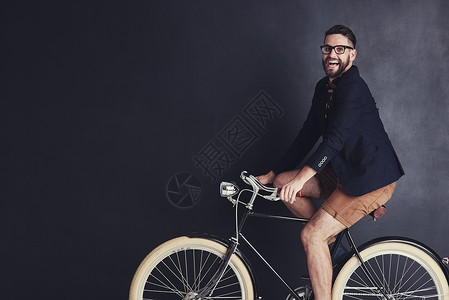 我随心所欲地骑自行车 一个时髦的年轻人在工作室骑自行车的肖像背景图片