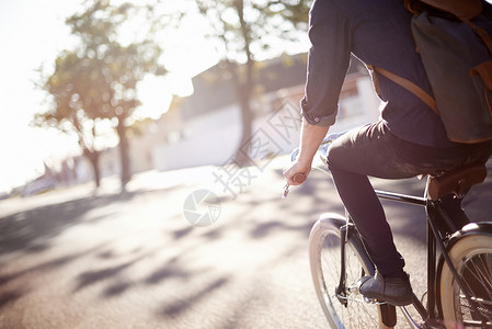旅行的生态友好方式 一个年轻人在户外骑着单车晴天骑术背包爱好街道自行车成年人男人成人绿色背景图片