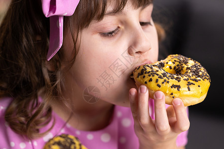 吃甜甜圈女孩年轻饥饿的女孩吃甜甜圈的画像 女性的嘴咬了一条面包 特写女人吃甜甜圈 美味 甜美 在家庭背景下爱吃甜食背景