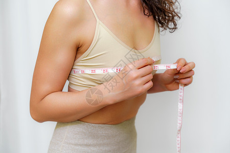 在家里用卷尺测量乳房的苗条女人的剪影 特写 面目全非的欧洲女性在室内检查减肥饮食或抽脂的结果 健康的生活方式测量腹部营养女士健身背景图片