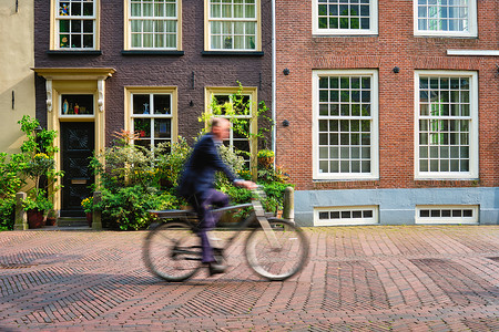 荷兰代尔夫特街骑自行车的骑自行车的人在荷兰非常流行的交通方式房子路面运输街道娱乐房屋风景陆运运动鹅卵石背景图片