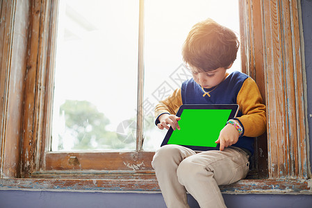 这些天的孩子都跟科技有关 一个小男孩坐在窗台上时用平板电脑 被割伤的镜头拍下来背景图片