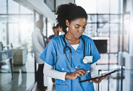 更少的纸张 更多的诊断 一位年轻医生在医院和她的同事在后台使用数字平板电脑的镜头背景图片