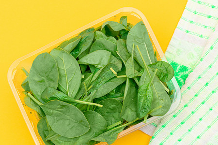 黄色背景透明塑料套件中新鲜的婴儿菠菜叶新片活食树叶食物植物绿色草本植物绿叶沙拉蔬菜减肥背景图片