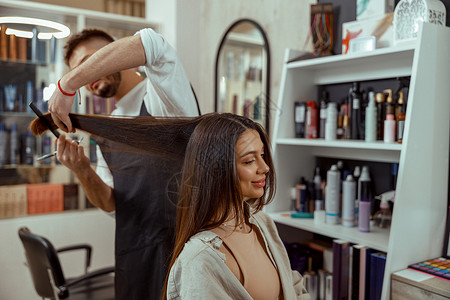 专业理发师 在理妇女头发时用梳梳子的理发师职业高清图片素材