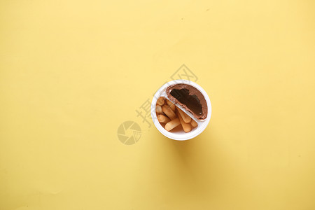 黄底的容器中装有巧克力夹面奶油的面包棒背景图片