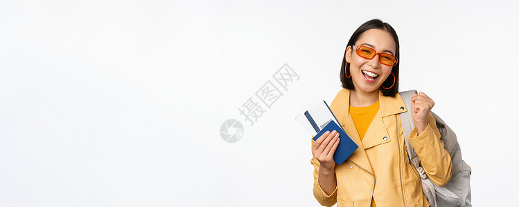 快乐的亚洲女孩去度假 拿着护照和机票 肩上背着背包 站在白色背景上出国旅行的年轻女游客太阳镜办公室工作室广告女士大学情感企业家情背景图片