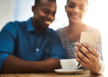认识你是约会的一部分 拍摄的是一对年轻男女在咖啡店约会时一起使用手机放松高清图片素材