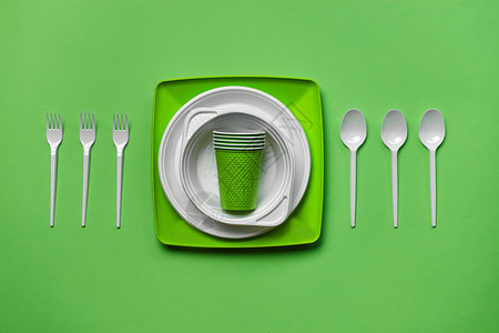 一次性塑料餐具在绿色背景的五颜六色的塑料一次性餐具与拷贝空间 野餐用具的概念 顶视图 选择性的焦点 特写工具外卖杯子派对盘子咖啡店午餐产品商品背景