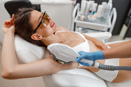 在美容院用ipl 机器在毛皮照片上放大手术时 女性客户在眼镜中的女客户背景图片