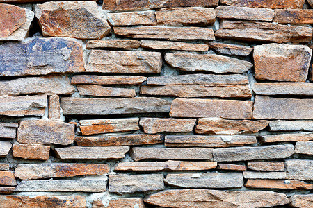 锋利石头墙的纹理与沙石相隔鹅卵石石头饰面石长方形力量石工花岗岩马赛克砂岩棕色背景