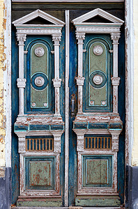 旧的有风气的木制门门 内装雕刻元素和在旧房子入口处的对称模式背景图片