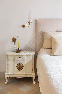 古典卧室用蜡烛和鲜花放在舒适床铺附近的木制床桌边的壁炉上 而这种房间则比较舒适复古的高清图片素材