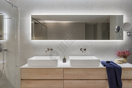 现代浴室内有木架 两个白色水槽和大镜子 深蓝色毛巾和装饰用的鲜花背景图片