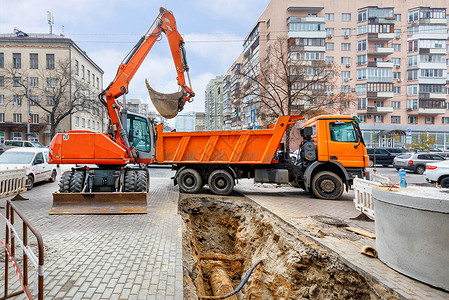 一辆挖土机和一辆卡车 用于修理市区街道的取暖干线高清图片
