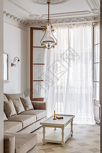客厅以古老的风格装饰 用瓷地板 打开阳台和挥舞窗帘 从走廊到沙发 咖啡桌和回旋吊灯都能看到背景图片