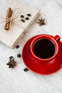 新鲜的热浓缩咖啡 红杯咖啡中的咖啡豆和背景浅薄的手工艺笔记本背景图片