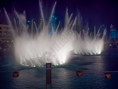 阿联酋迪拜塔夜里在城里用灯光跳舞的喷泉办公室投影机吸引力乐趣展示旅游市中心民众照明购物中心背景