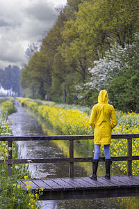 春生带黄雨衣和橡胶靴的年轻女青年衣服天气橡皮雨鞋下雨裙子季节女性女孩鞋类背景图片