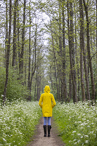 春生带黄雨衣和橡胶靴的年轻女青年下雨女性橡皮季节乐趣鞋类女士雨鞋公园天气背景图片