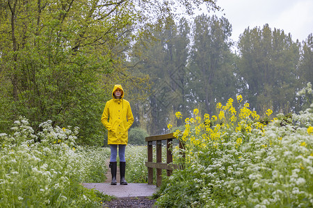 春生带黄雨衣和橡胶靴的年轻女青年季节裙子鞋类乐趣天气女士雨鞋衣服公园女性背景图片